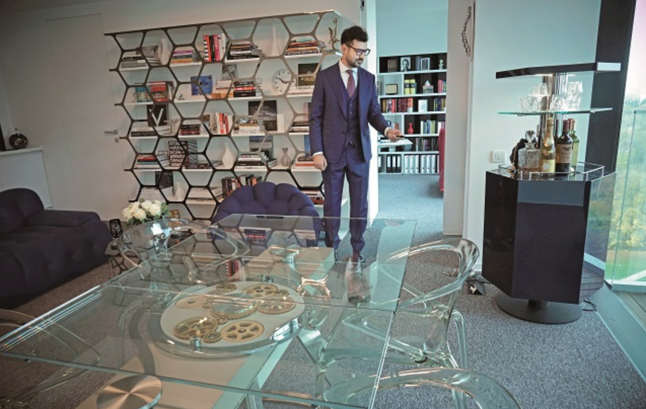 Tudor Coltan in his Bucharest office — architectural bookshelf, glass table, city view